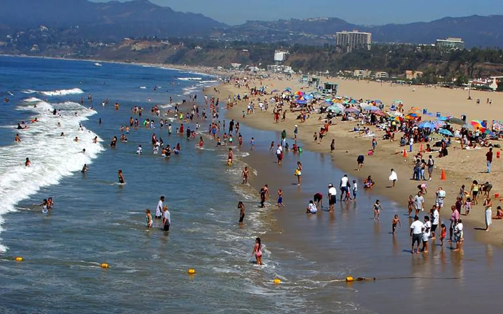 Sandy beach at Santa Monica State Beach with lifeguard towers and beachgoers in the Pacific Ocean